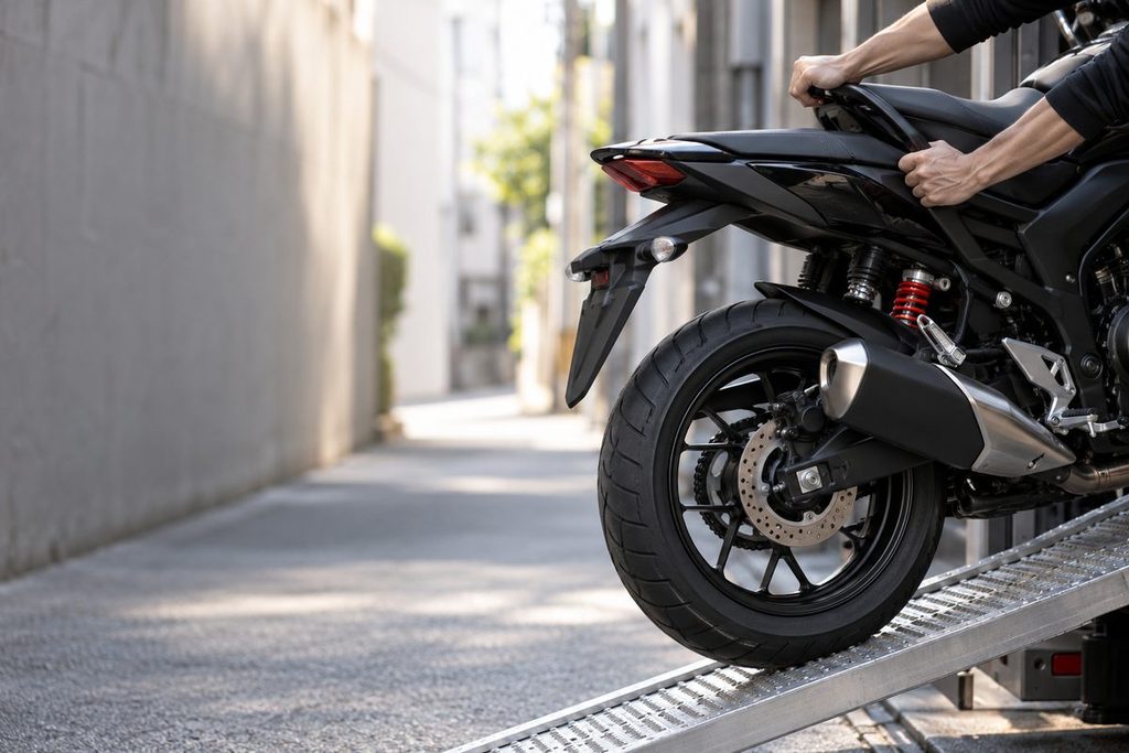 大阪の路地で、バイクを積載用スロープへ押し上げる手元。